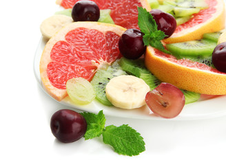 Assortment of sliced fruits on plate, isolated on white
