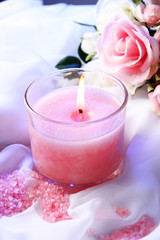Beautiful candle with flower on white cloth, close up