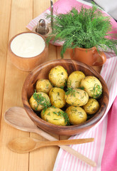 Boiled potatoes on wooden bowl near napkin on wooden table