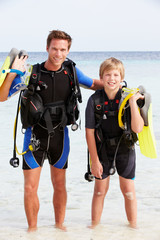 Father And Son With Scuba Diving Equipment On Beach Holiday