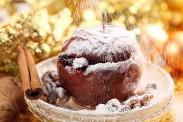 Baked apple on plate and pouring sugar