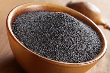 Bowl with poppy seeds and dry poppy pod in background.