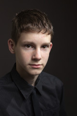Fototapeta premium Portrait of a teenage boy against dark background