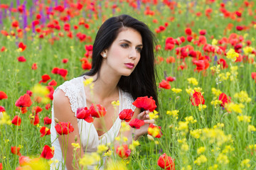 Naklejka premium beautiful girl with long hair sitting in the poppy field