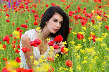 Obraz na płótnie Canvas beautiful girl with long hair sitting in the poppy field