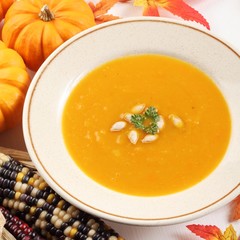 Plate with pumpkin soup and autumn decorations.