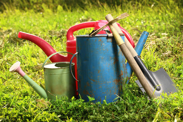 Old watering cans and shovel on grass