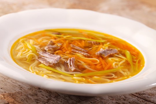 Beef broth with vegetables, noodles and meat.