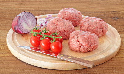 Raw meat homemade burgers with onion and tomatoes