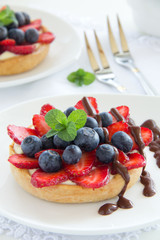 Sand tartlet with vanilla cream, strawberries and blueberries.
