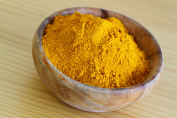 Tumeric powder in wooden bowl, close up