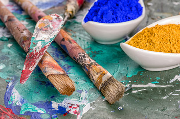 Pinsel, Spachtel und Farbpigmente auf einer Holzpalette