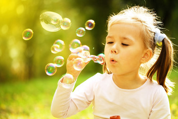Little girl is blowing a soap bubbles