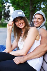 Young happy smiling sporty couple sitting on bench