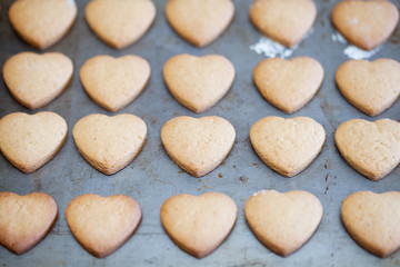 Horizontal rows of heart shapes cookies on baking tray