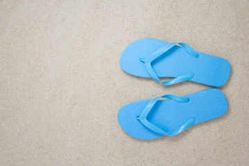 Fototapeta na wymiar blue flip flops on the white beach sand