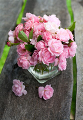 small pink garden roses on wooden surface