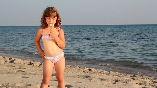 beautiful little girl eat ice cream on beach