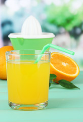 Citrus press, glass of juice and ripe oranges