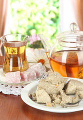 Tasty halva with tea on table in room