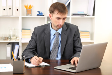 Naklejka premium Young businessman in office at his workplace