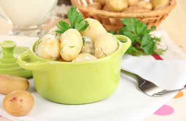 Tender young potatoes with sour cream and herbs in pan