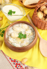Tender young potatoes with sour cream and herbs in wooden bowl