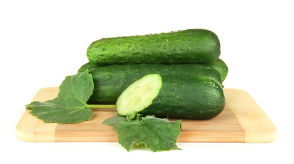 Tasty green cucumbers on wooden cutting board, isolated on