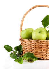 Juicy green apples with leaves in basket, isolated on white