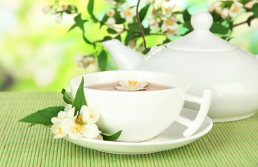 Obraz na płótnie Canvas Cup of tea with jasmine, on bamboo mat, on bright background