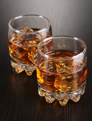 Brandy glasses with ice on wooden background