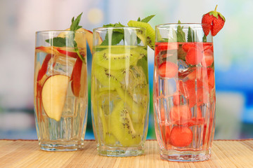 Glasses of fruit drinks with ice cubes on table in cafe