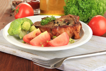 Piece of fried meat on plate on wooden table close-up