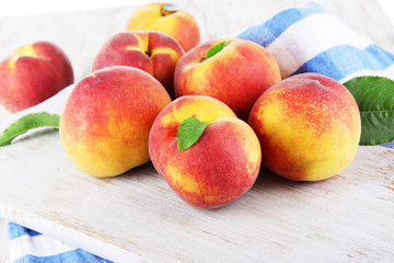 Peaches on board on napkin on table on wooden background