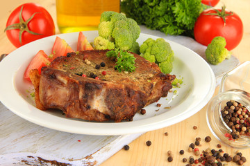 Piece of fried meat on plate on wooden table close-up