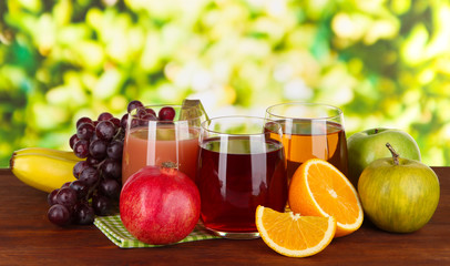Glasses of fresh juice on table on bright background