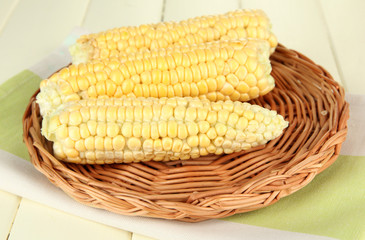 Fresh corn on wicker mat, on wooden background