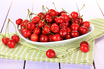 Cherry berries in bowl on wooden table close up