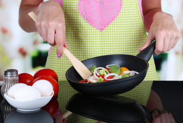 Hands cooking vegetable ragout in pan in kitchen