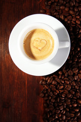 Cup of coffee with coffee beans on wooden background