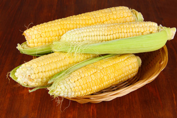 Fresh corn vegetable in wicker basket on wooden table