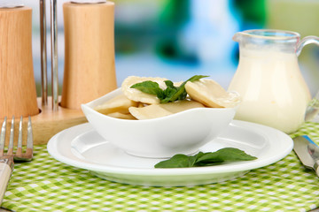 Tasty dumplings on white plate, on bright background