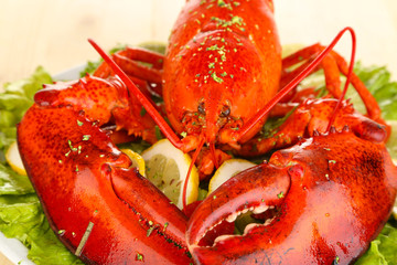 Red lobster on platter with vegetables on wooden table close-up