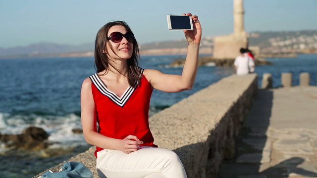 Woman taking photo of herself with smartphone by the sea