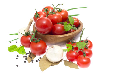 The branch of cherry tomatoes in a wooden bowl, onion, garlic, b