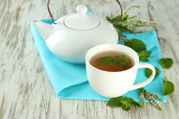Teapot and cup of herbal tea with fresh mint flowers