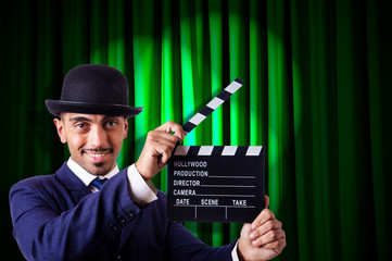 Man with movie clapper on curtain background