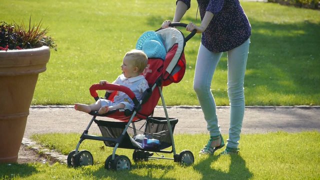 HD1080p25 Young woman pushes stroller with baby in the garden
