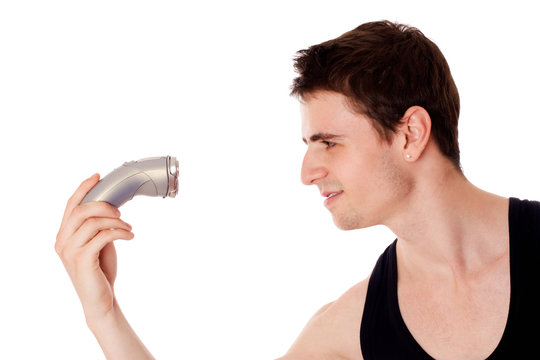 Young man shaving his beard off with an electric razor.
