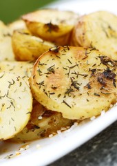 Close-up of plate with baked potatoes, spices, thyme and salt.